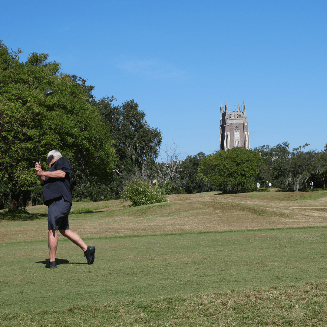 Person playing golf with Loyola campus in the background
